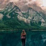 Woman standing at Klöntalersee in Switzerland with scenic mountain background.